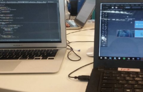 Laptops on a table during the Startup Weekend, one with code and one with the prototype in progress
